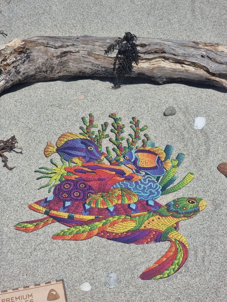 Turtle-shaped wooden jigsaw puzzle with tropical fish and coral on a sandy beach